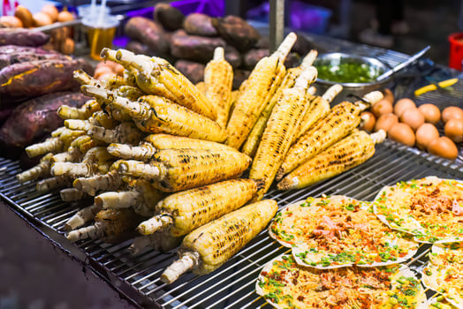Grilled corn near vietnamese pancake with eggs, sausages and sauces in vietnamese night market in Da Lat photo