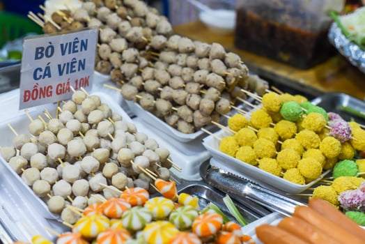 Many snacks and seafood in vietnamese night market in food festival sign beef ball, fish ball, price 10 000 dongs photo
