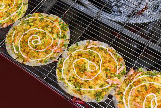 Grilled vietnamese pancake with eggs, sausages and sauces in vietnamese night market in Da Lat photo