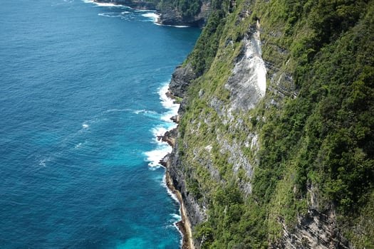Beautiful landscape aerial view of cave in rocky at the sea with foam waves and splash water. Travel destination seascape of summer calm ocean in Bali at Indonesia photo