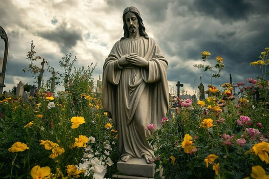 Jesus Christ statue surrounded by flowers in a cemetery, against a dramatic sky photo