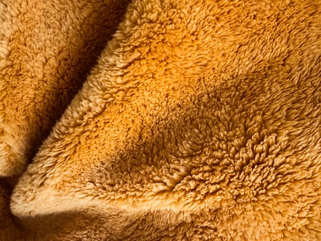 Soft golden fabric close-up reveals intricate textures and patterns in bright light photo