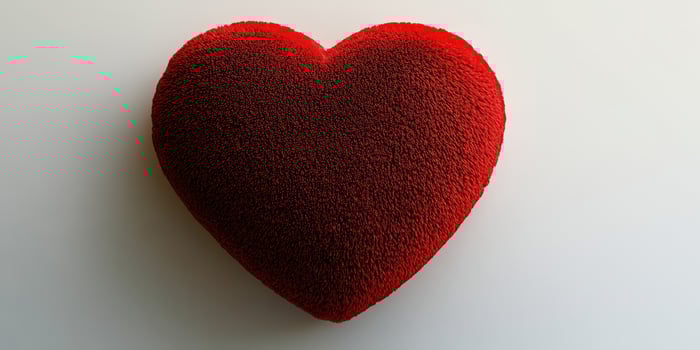 Heart-shaped red cushion on a white surface ideal for decoration or gifting photo