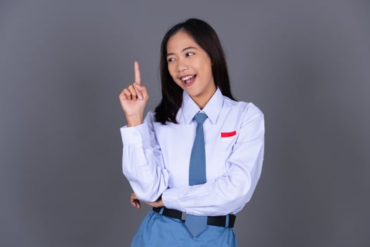 Indonesian Female High School Student in Uniform Smiling While Pointing Finger photo