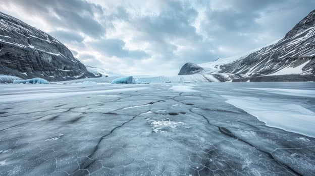 A serene icy landscape with cracked ice and mountains under a cloudy sky. photo