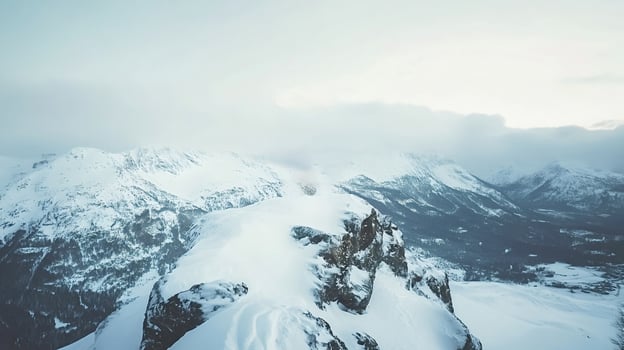 Snowy mountain peaks rising above a valley covered in clouds during winter photo