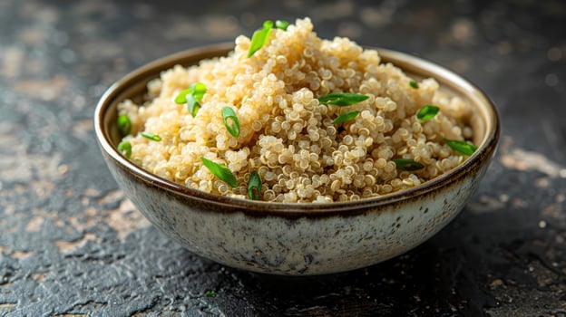 A bowl of cooked quinoa garnished with chopped green onions on a textured surface. photo