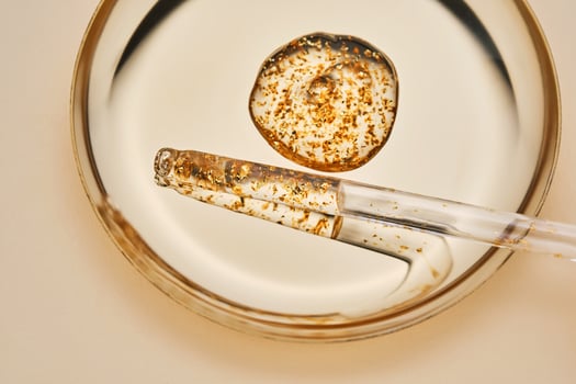 24 k gold facial serum in a pipette on a gold background. photo