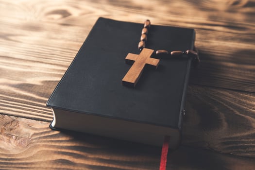 A bible and a rosary on a wooden table photo