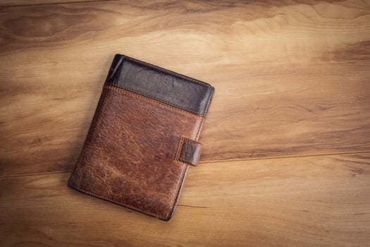 A brown leather wallet sitting on a wooden table photo
