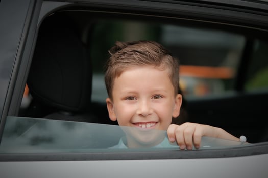 Happy kid boy looking out the car window. photo