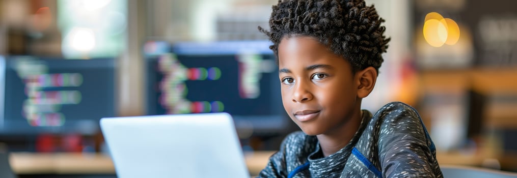 A young boy is sitting in front of a laptop photo