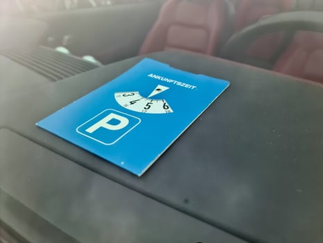 Blue parking disc showing arrival time inside car windshield photo