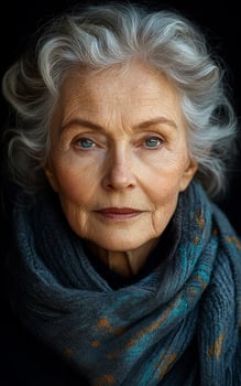 A woman with gray hair and blue eyes is wearing a scarf. She has a serious expression on her face photo