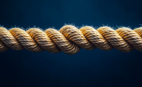 A rope is twisted and knotted. The rope is brown and the knot is in the middle of the rope photo