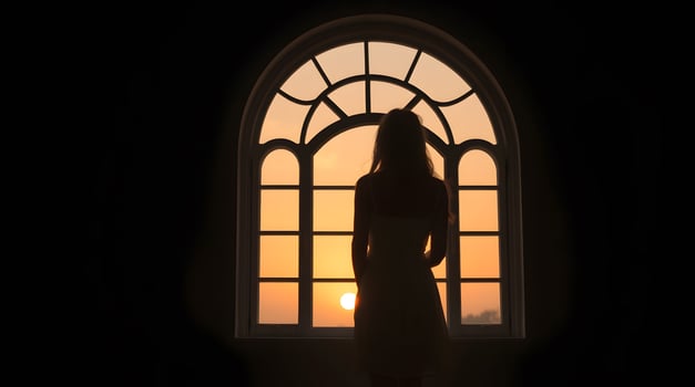 Woman Silhouette Looking at Sunset Through Window for Peaceful Moment photo
