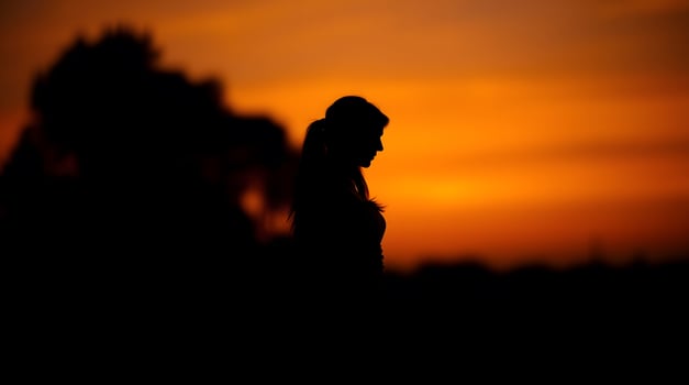 Silhouette of Woman at Sunset with Dramatic Orange Sky Backdrop photo