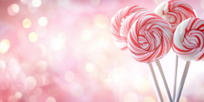 Colorful lollipops on sticks against a soft pink background. photo