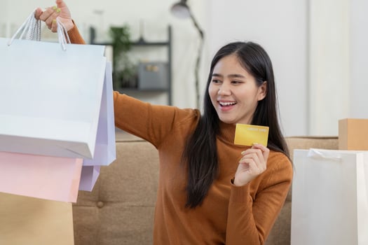 Happy woman shopping online at home with credit card and shopping bags, enjoying retail therapy. photo
