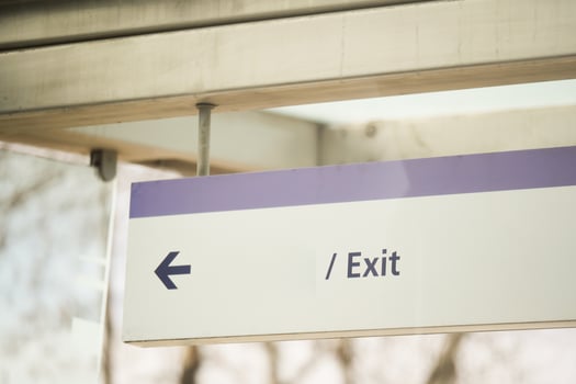 Sign pointing left toward exit in a public space photo
