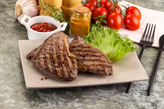 A plate of steak with vegetables and condiments photo