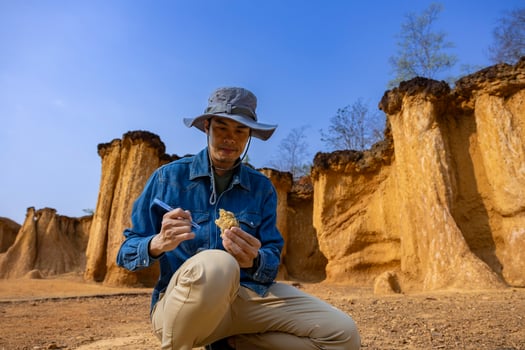 Asian geologist is exploring and surveying the sample rock on the natural sandstone canyon quarry site for scientific research and archeology for understanding mother earth photo