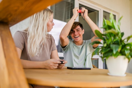 Joyful man and woman playing games on terrace. Technology and game console concept photo