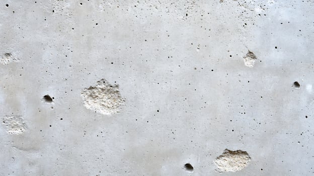 Light gray concrete wall texture with holes. photo