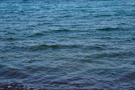 Tranquil waves gently ripple over the serene blue waters of a secluded beach at sunset photo