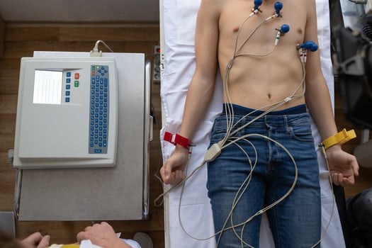 A female doctor performs an ECG on a young man in a hospital room, carefully monitoring his heart health during a routine checkup. photo