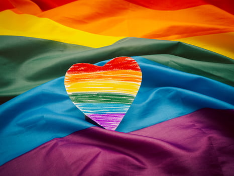 A rainbow heart shape symbol made from paper over the rainbow flag or LGBT flag photo