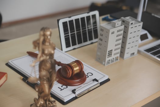 Lawyer's desk with a gavel, a book, a laptop, and a solar panel photo