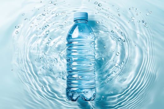 Clear plastic water bottle submerged in rippling blue water background photo