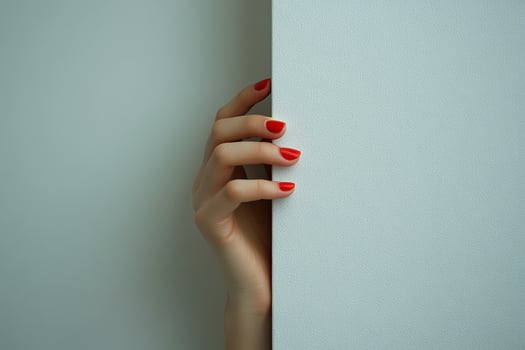 A well-groomed hand of a young woman with a red manicure playfully touches an empty white wall. Generated by artificial intelligence photo
