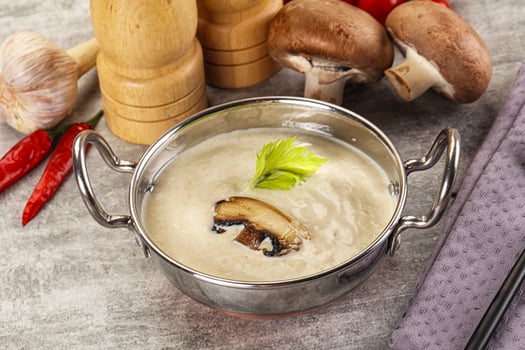 A bowl of soup with a spoon and a knife photo