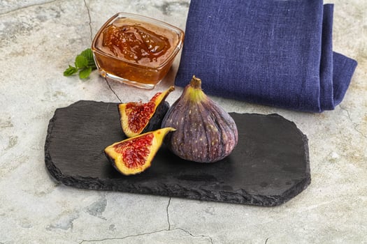 A black slate serving platter with figs and a glass of tea photo