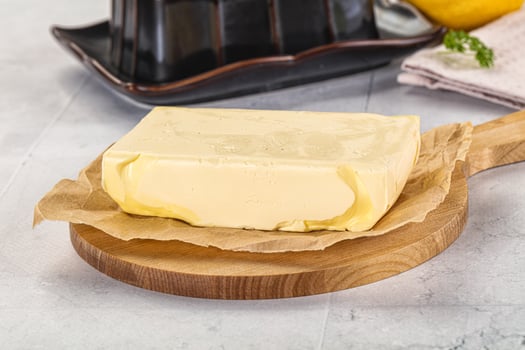 A piece of butter sits on a wooden cutting board photo