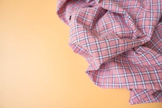 Pink plaid fabric with soft folds on beige background, textile material close-up, copy space. photo