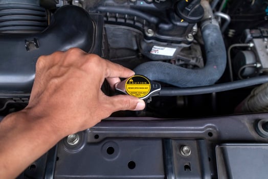 A mechanic's hand holding the radiator cap and checking the car radiator water. photo