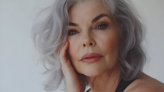 Portrait of elegant mature woman with grey hair and flawless makeup posing gracefully photo