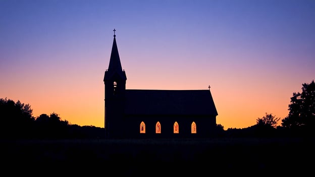 Silhouette of a church at twilight with colorful sunset backdrop in serene countryside photo