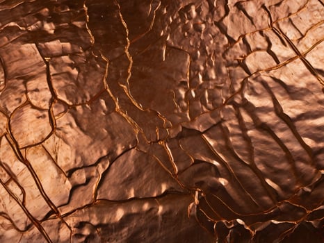 A macro perspective of textured copper with a deep reddish-gold shine. photo