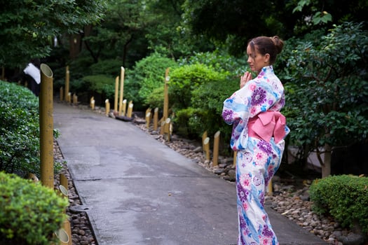Woman in Floral Kimono Meditating on Garden Pathway photo