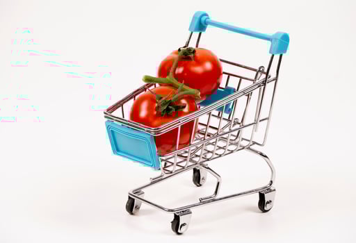 Small cart with fresh red tomatoes on a white background photo