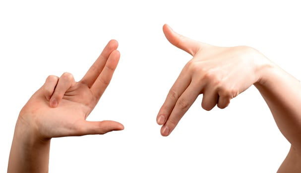 Female hands forming an L-shaped frame, fingers positioned to visualize a scene, shot, or photo