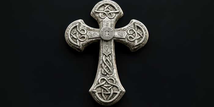 Intricate stone cross with Celtic designs displayed on a dark background photo