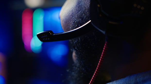 Close up of headset mic used by professional streamer competing in intense online multiplayer videogame live from home. Focus on headphones microphone used by man playing on gaming PC, camera A photo