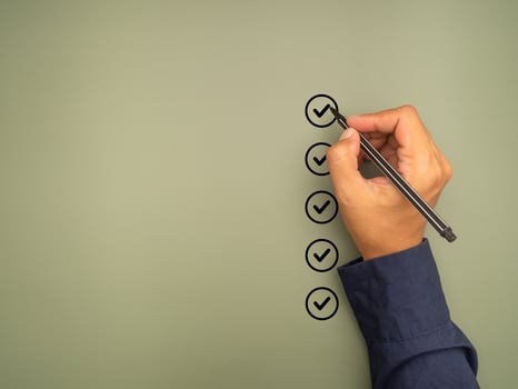 Hand holding a pen check-marking on the checklist box on a green background. photo