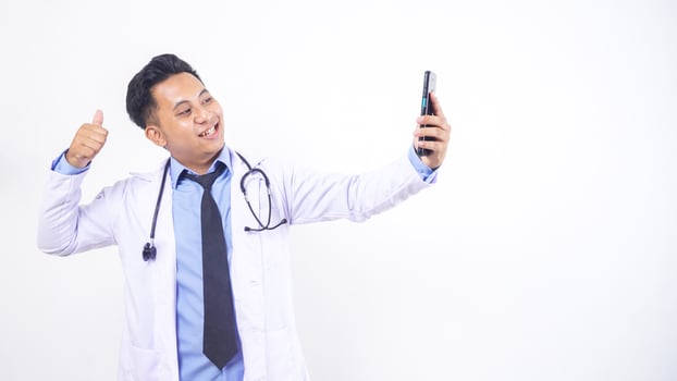 Asian Male Doctor Making Phone Call and Showing Thumb Up on White Doctor photo