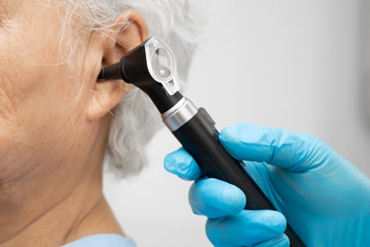 Otolaryngologist or ENT physician doctor examining senior patient ear with otoscope, hearing loss photo